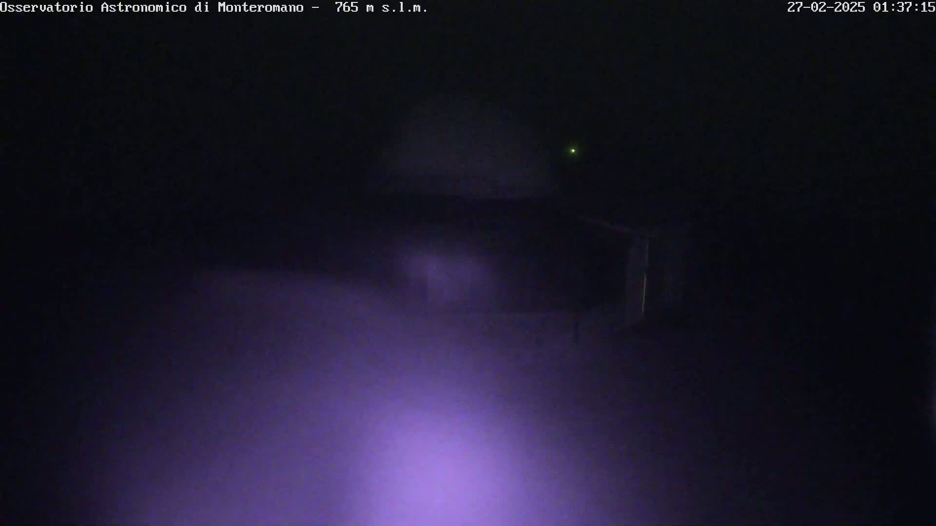A dark, foggy nighttime scene shows a building partially obscured by low-lying fog or mist.