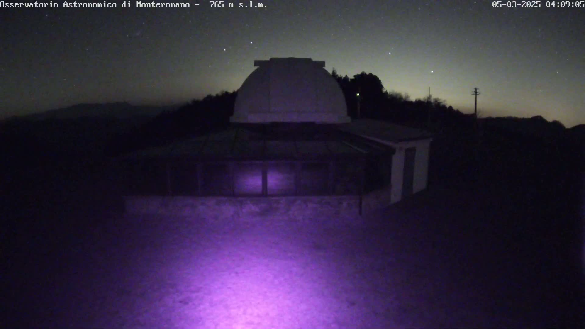 A dark, nighttime image shows an observatory building with a dome under a starry sky.
