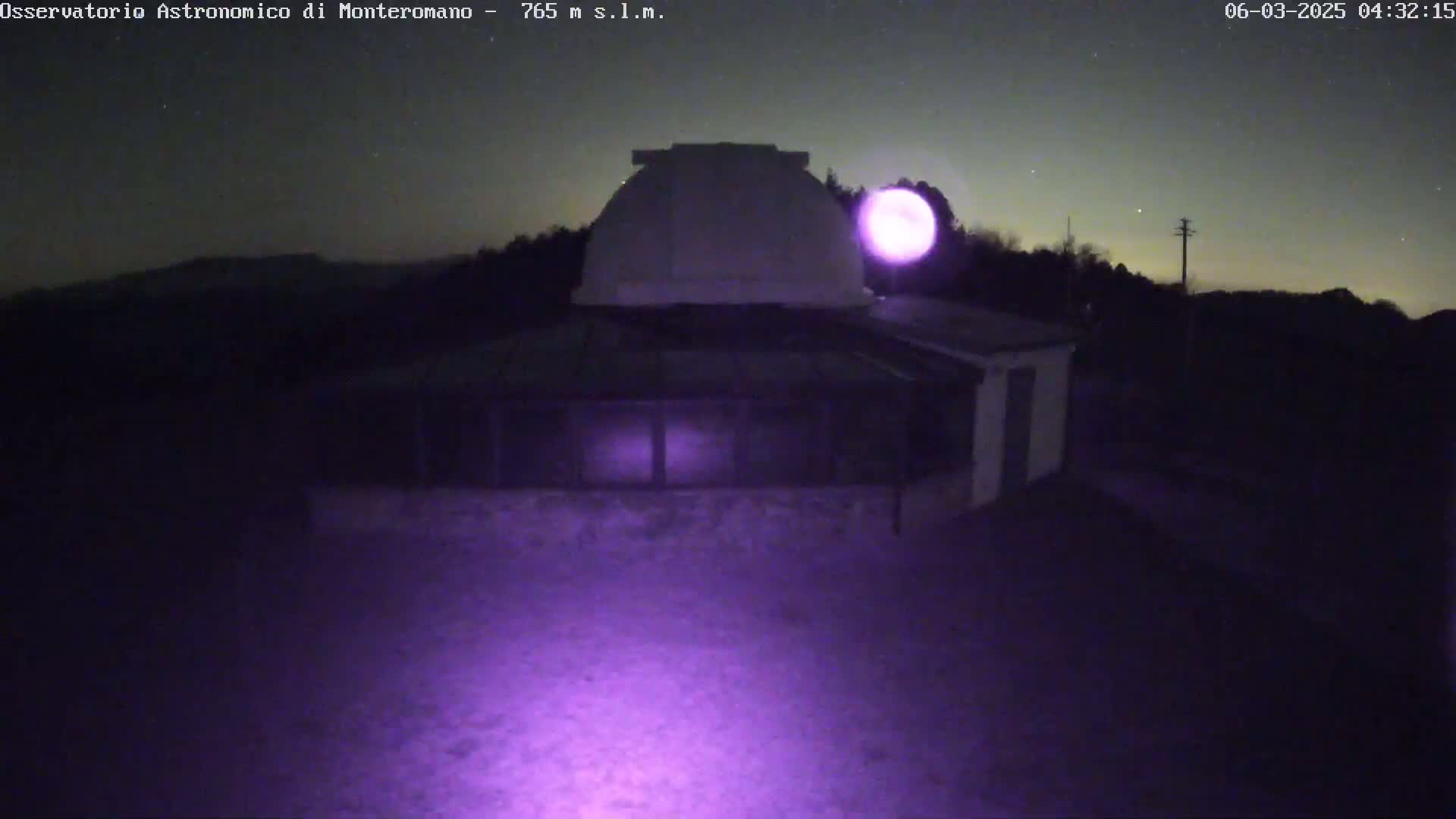 A low-light nighttime image shows a dome-shaped building, possibly an observatory, under a clear, starry sky with a bright moon.