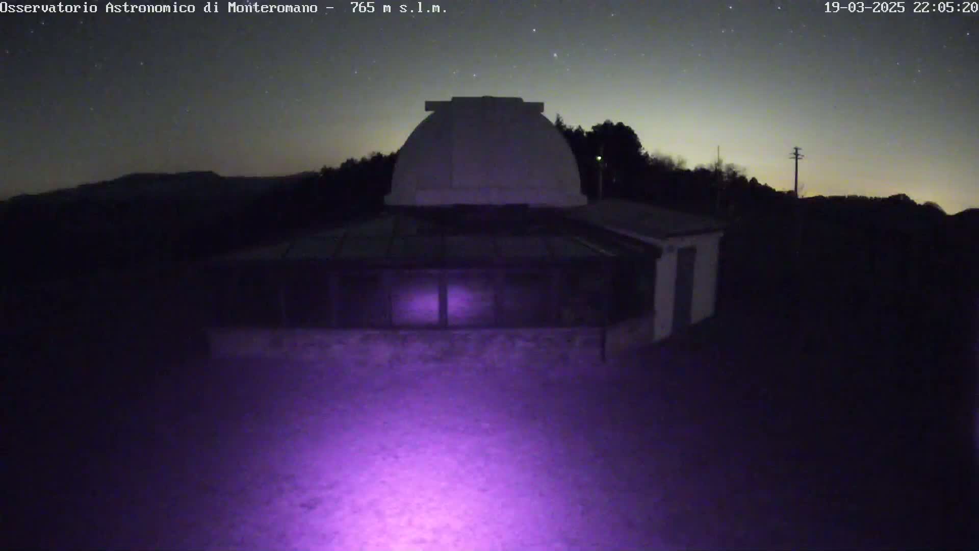 A nighttime view of an observatory building with a dome under a starry sky.