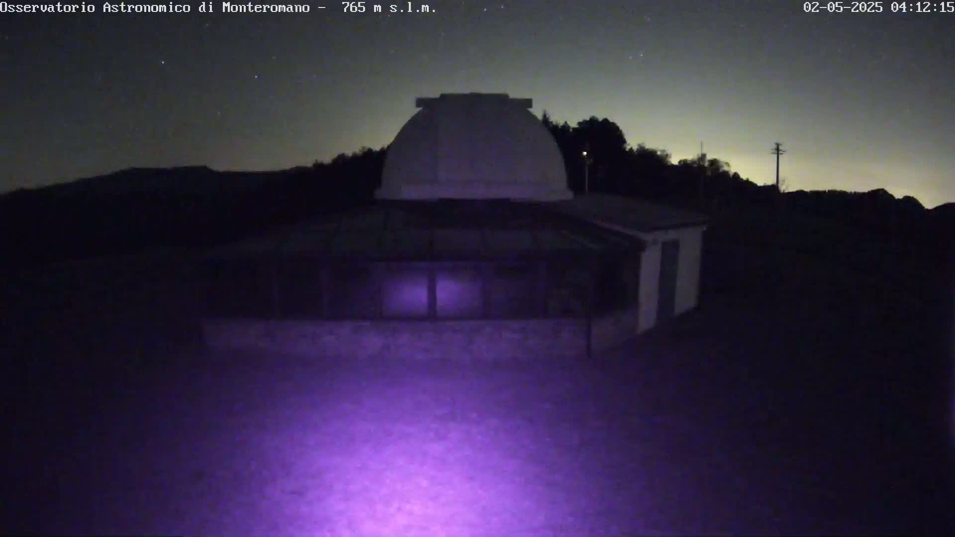 A low-light nighttime image shows an observatory building with a dome under a clear, starry sky.