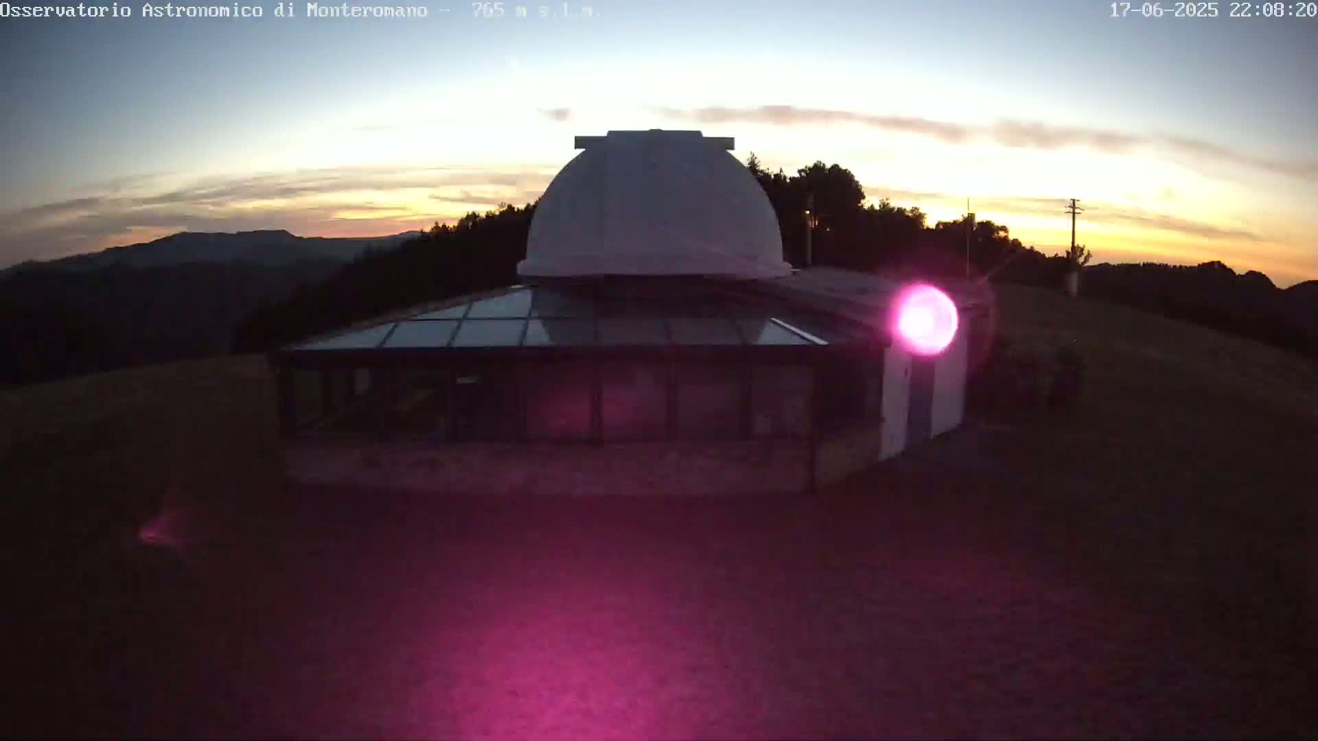 An observatory with a white dome sits atop a hill at sunset, under a mostly clear sky.