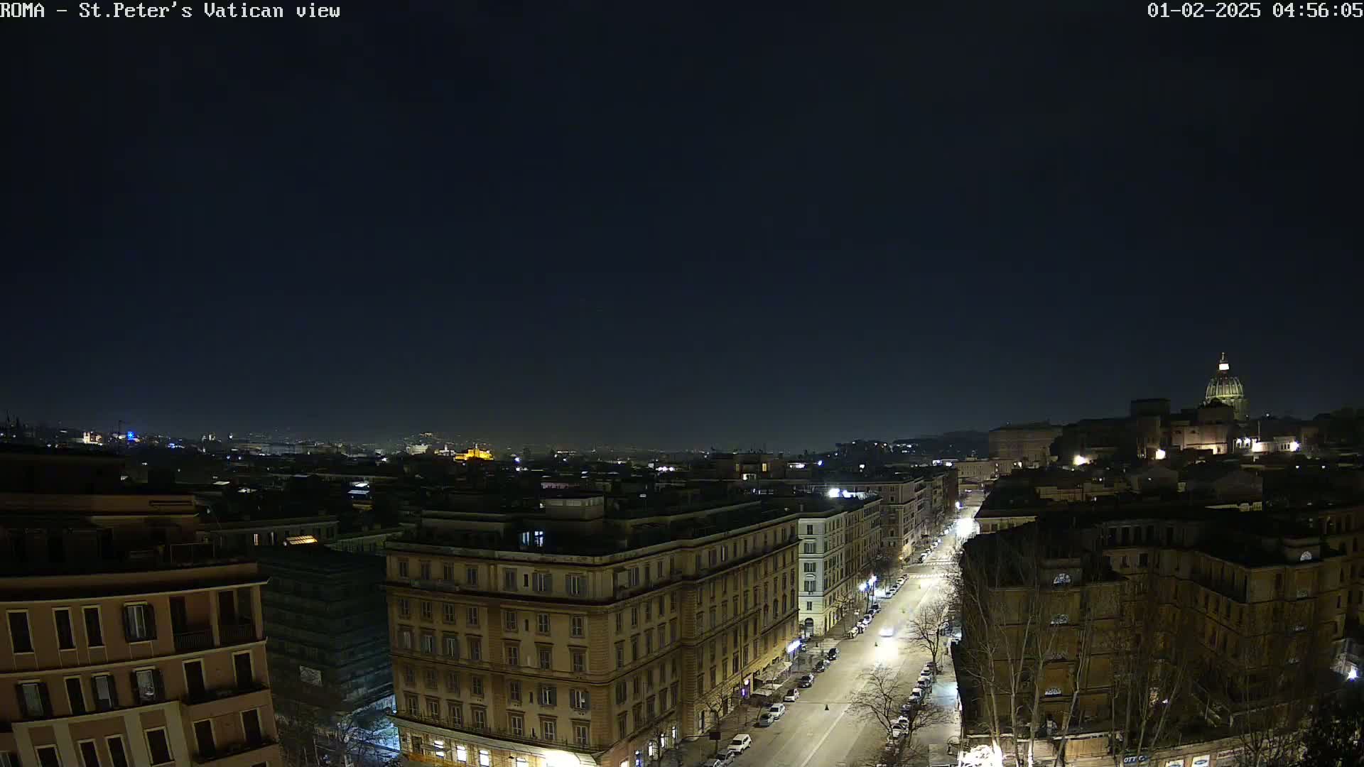 A nighttime, aerial view of a city street scene shows buildings illuminated against a dark sky.