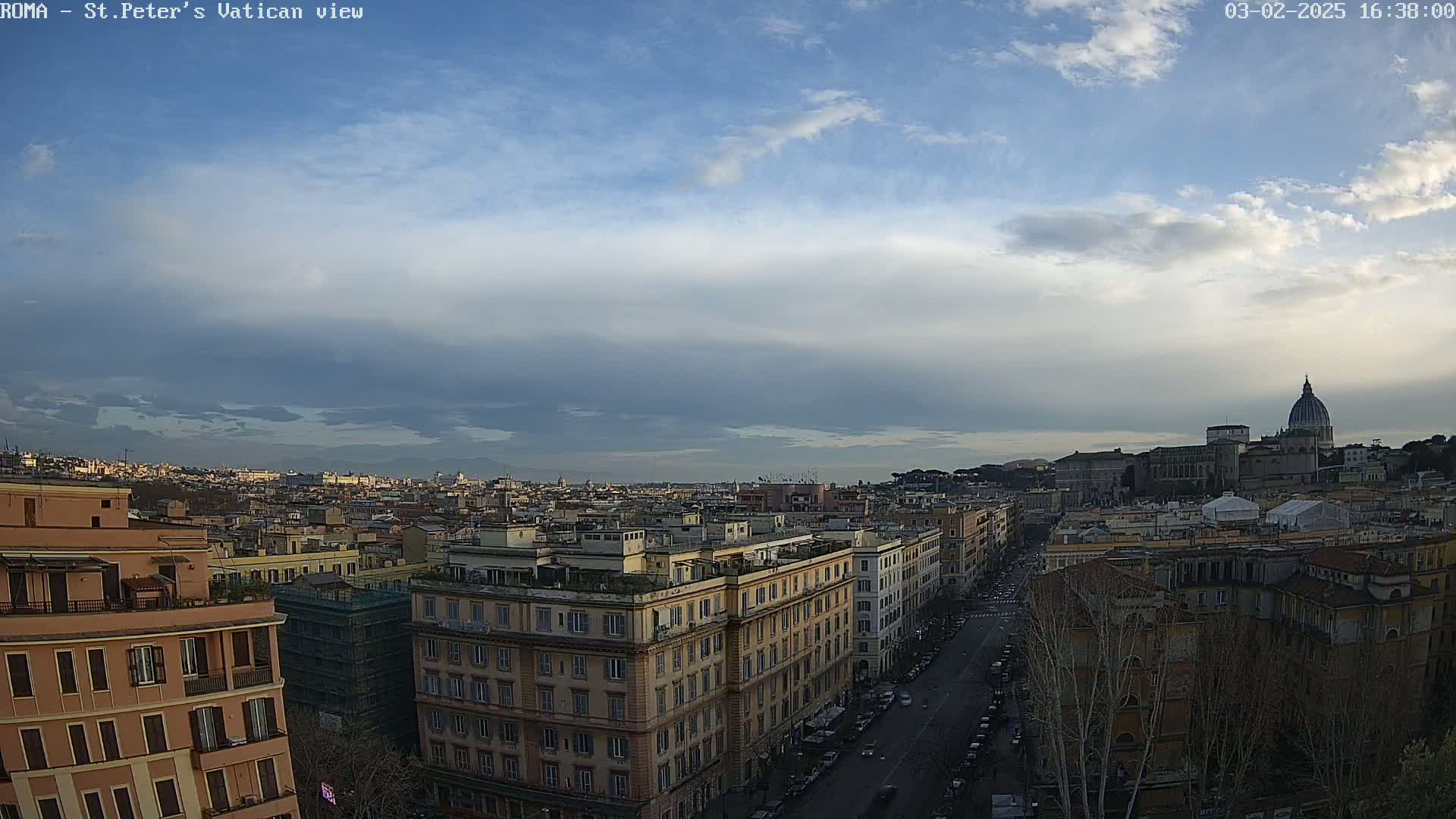 A partly cloudy daytime view of Rome, Italy, shows a cityscape with the dome of St. Peter's Basilica in the distance.