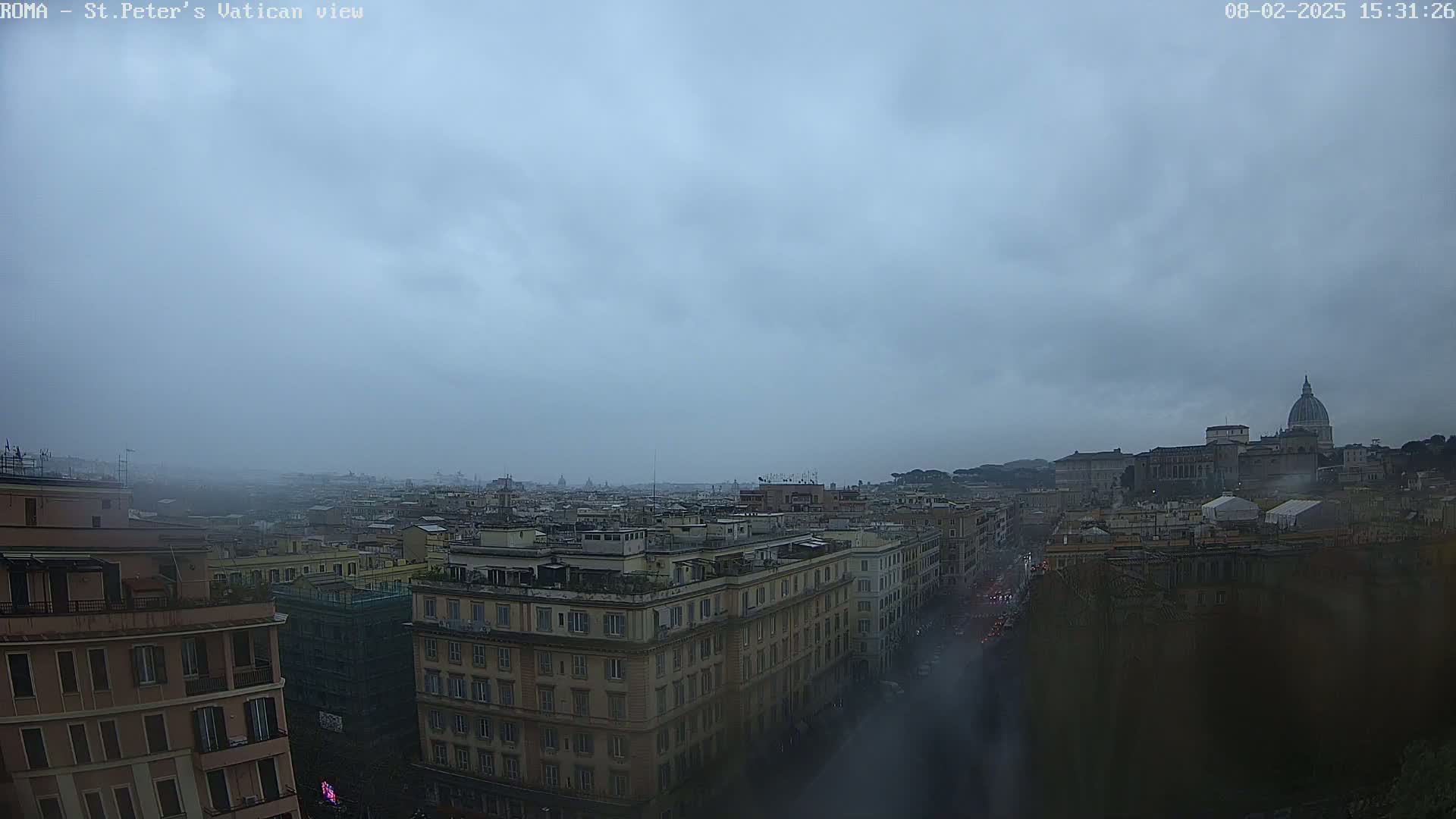 A hazy, overcast view of Rome, Italy, shows many buildings extending to the distance, where St. Peter's Basilica is visible.