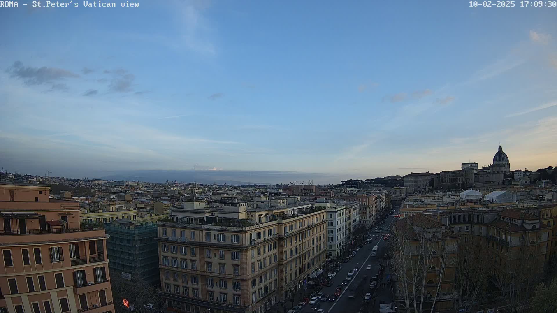 A mostly clear, twilight sky overlooks a cityscape of Rome, Italy, with St. Peter's Basilica visible in the distance.