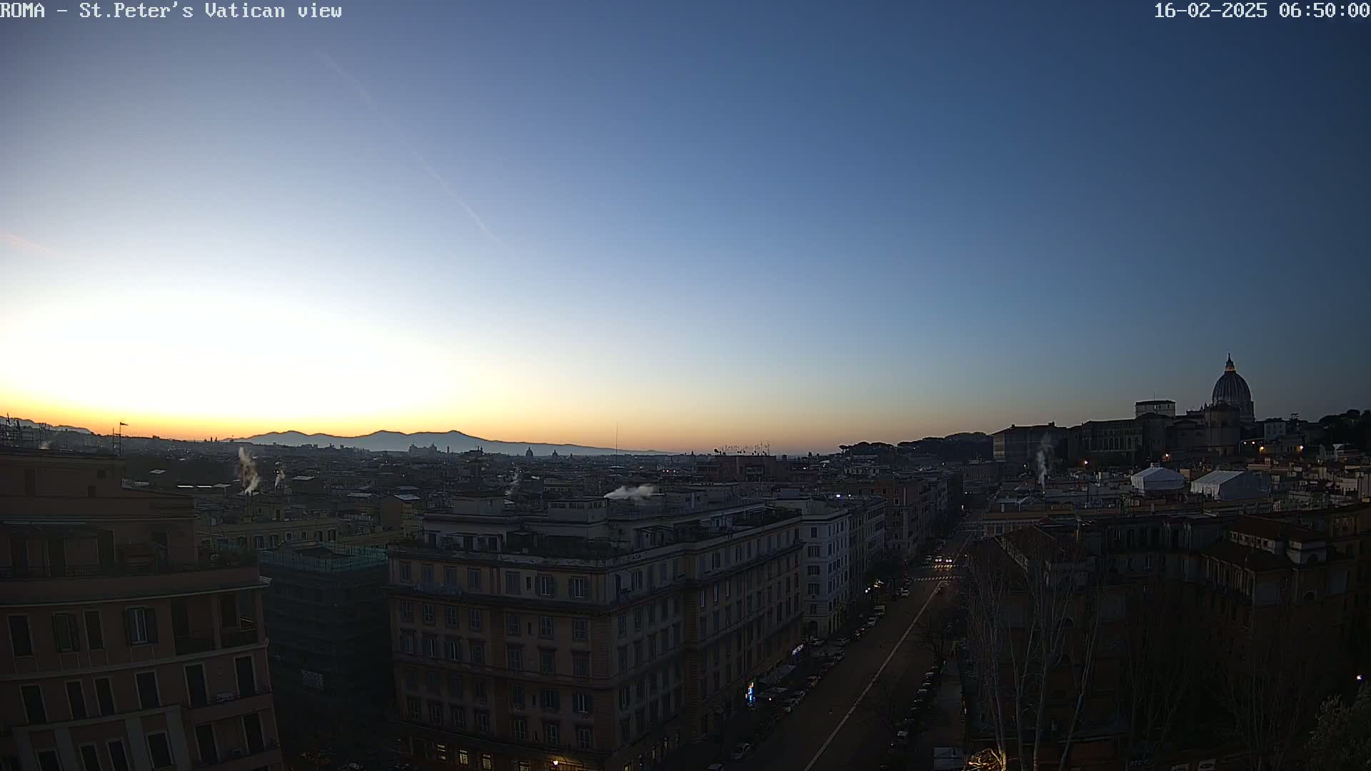 A cityscape at sunrise, with the dome of St. Peter's Basilica visible in the distance, under a clear sky.