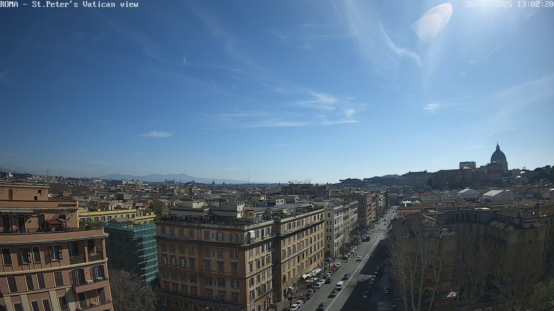 A sunny cityscape view shows a distant dome and cityscape extending to distant mountains under a mostly clear blue sky.