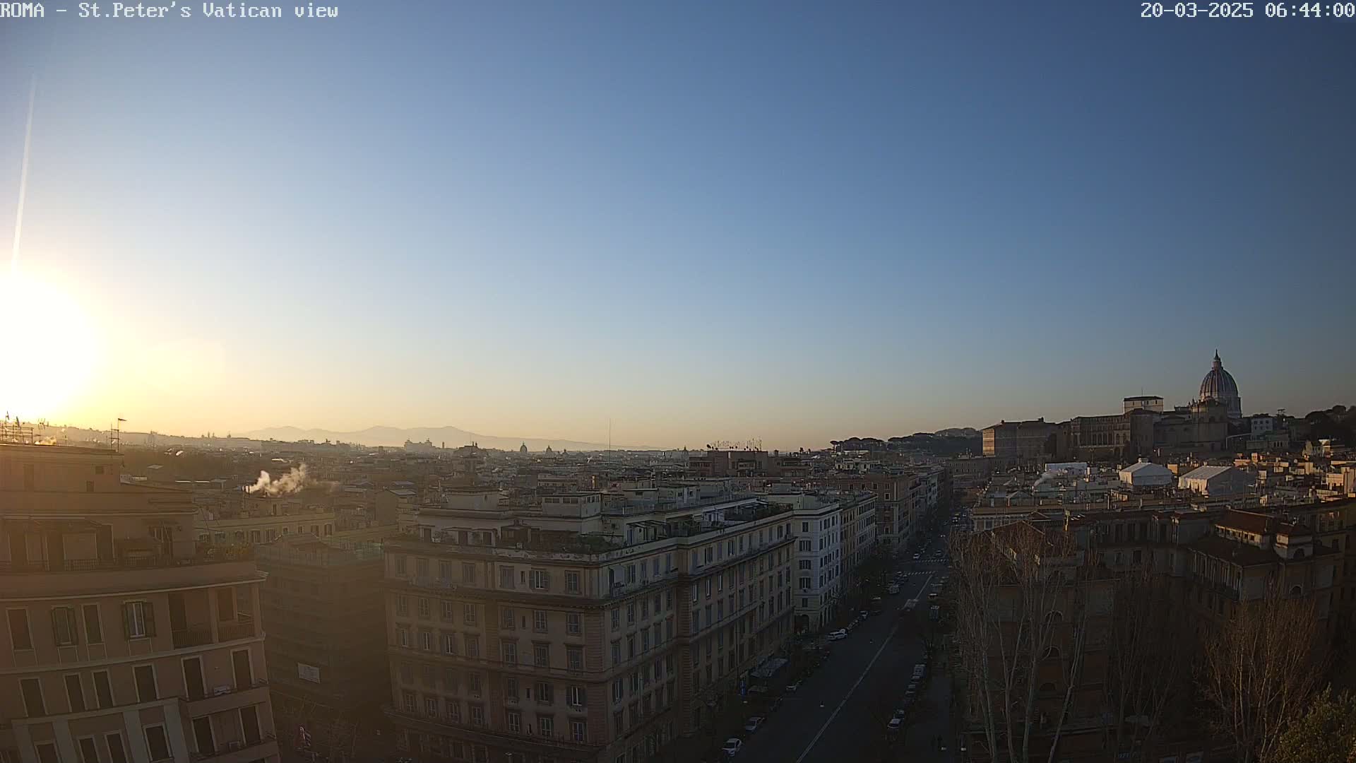 A clear sunrise illuminates a cityscape of Roman buildings, with St. Peter's Basilica visible in the distance.
