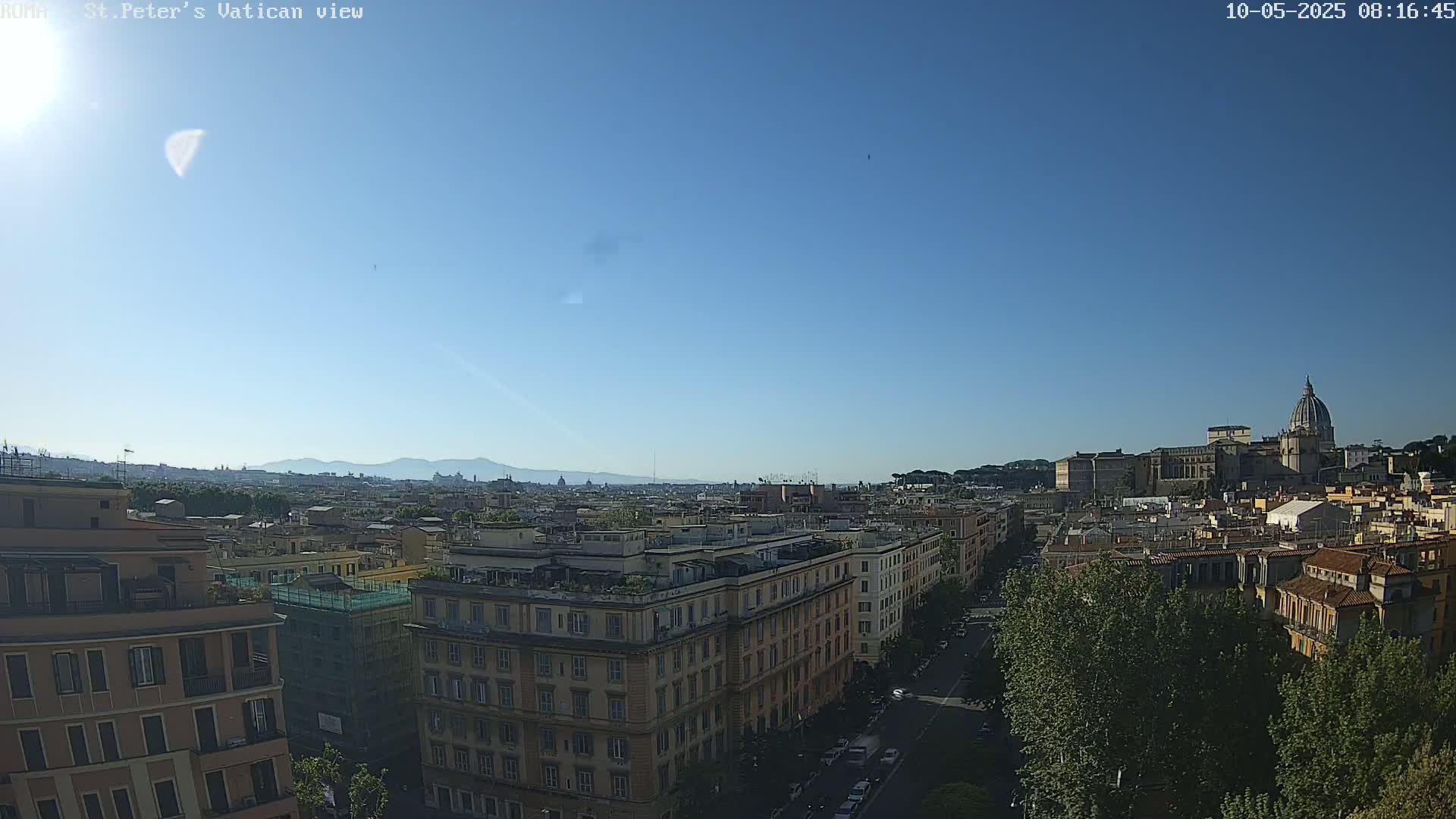 A sunny cityscape view shows a distant basilica with a dome, city buildings, and a clear blue sky.