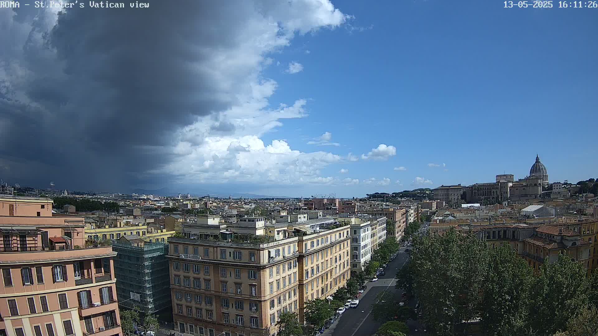 A partly cloudy sky with a large, dark storm cloud hangs over a cityscape featuring multiple buildings and a large dome in the distance.