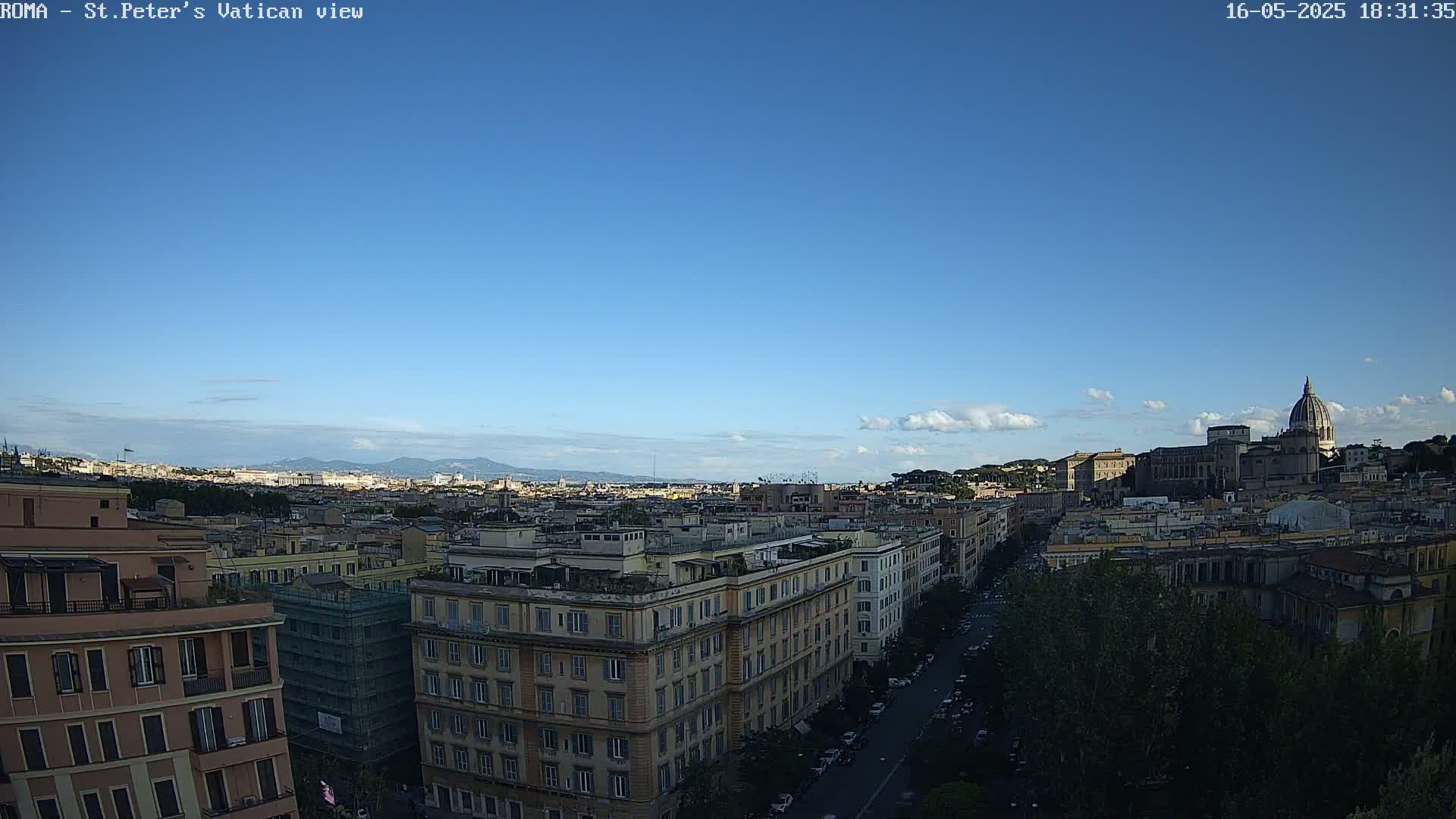 A clear blue sky overlooks a sprawling cityscape of Roman buildings and a distant dome under a mostly clear sky with a few small clouds.