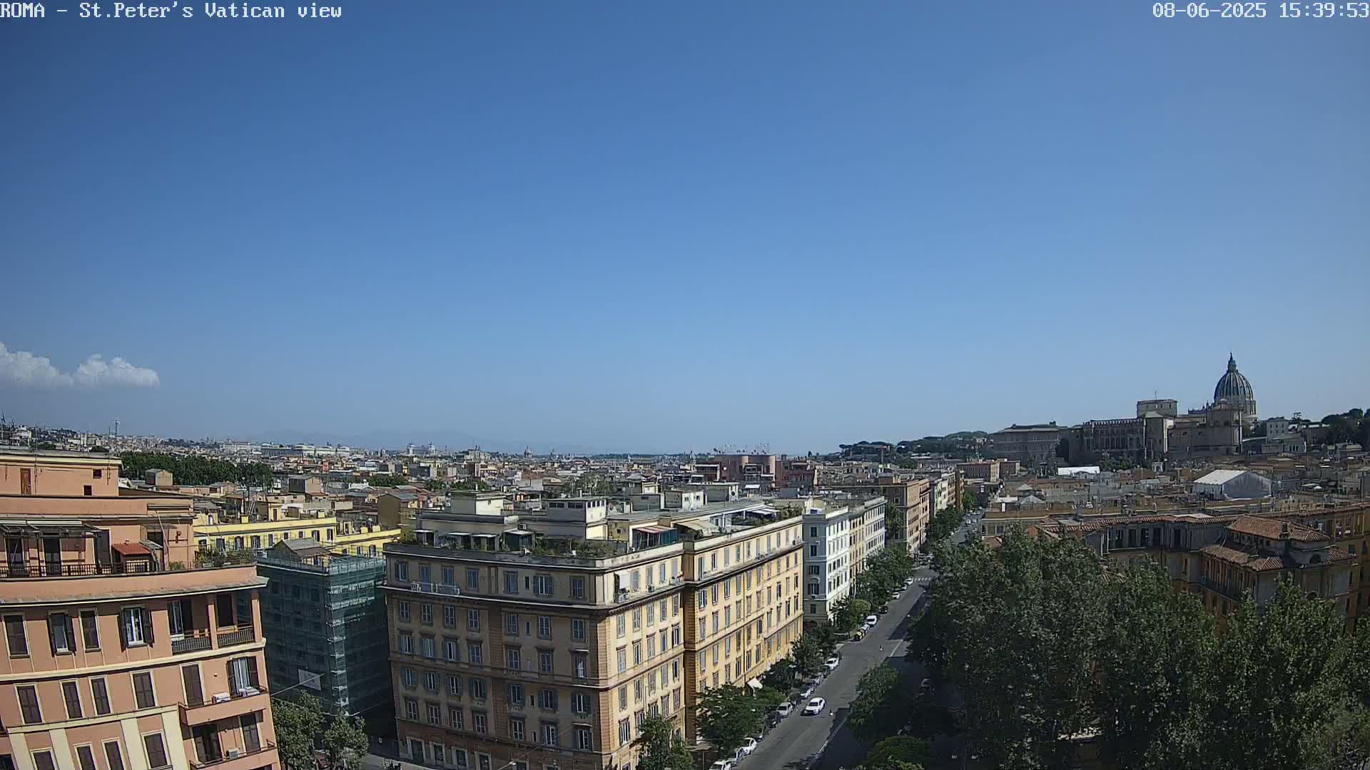 A panoramic view of Rome on a clear, sunny day shows a cityscape of buildings and streets leading to St. Peter's Basilica in the distance.