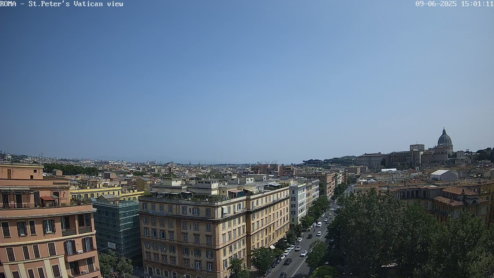 A clear, sunny day reveals a panoramic view of Rome, with St. Peter's Basilica visible in the distance and city buildings and streets stretching toward the horizon.