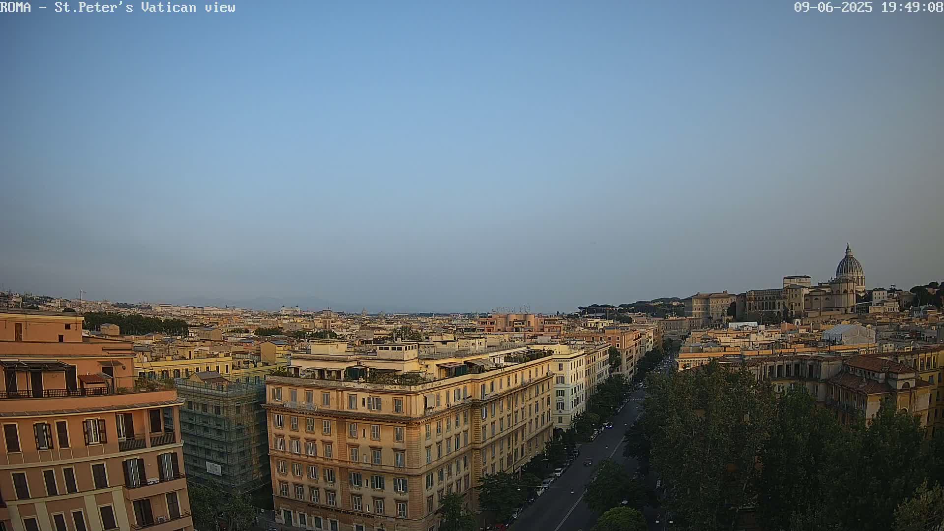 A high-angle view of Rome, Italy, on a clear, twilight sky shows a cityscape with St. Peter's Basilica in the distance.