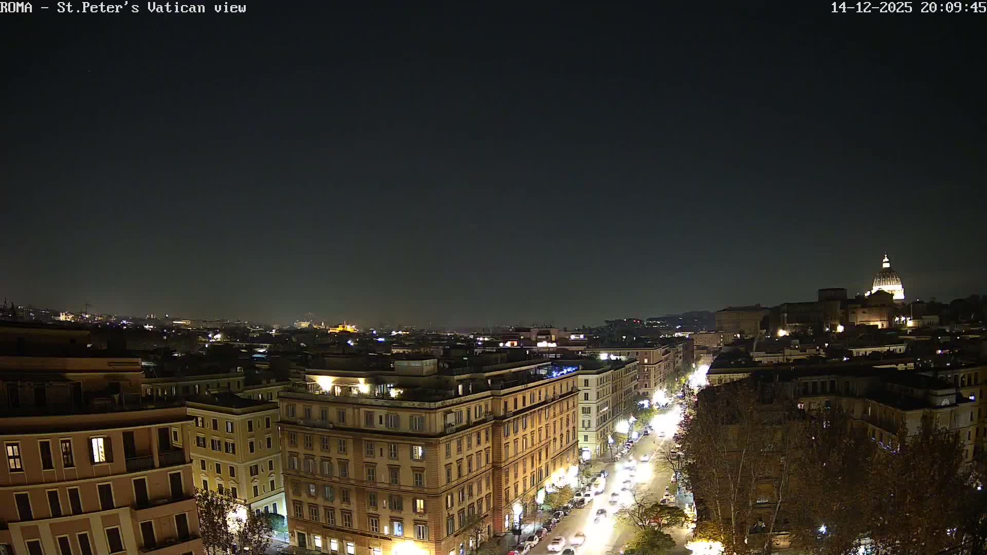 A bright, hazy, and partly cloudy sky illuminates a sprawling city with numerous buildings and a distant prominent dome, under a sun causing a visible lens flare.
