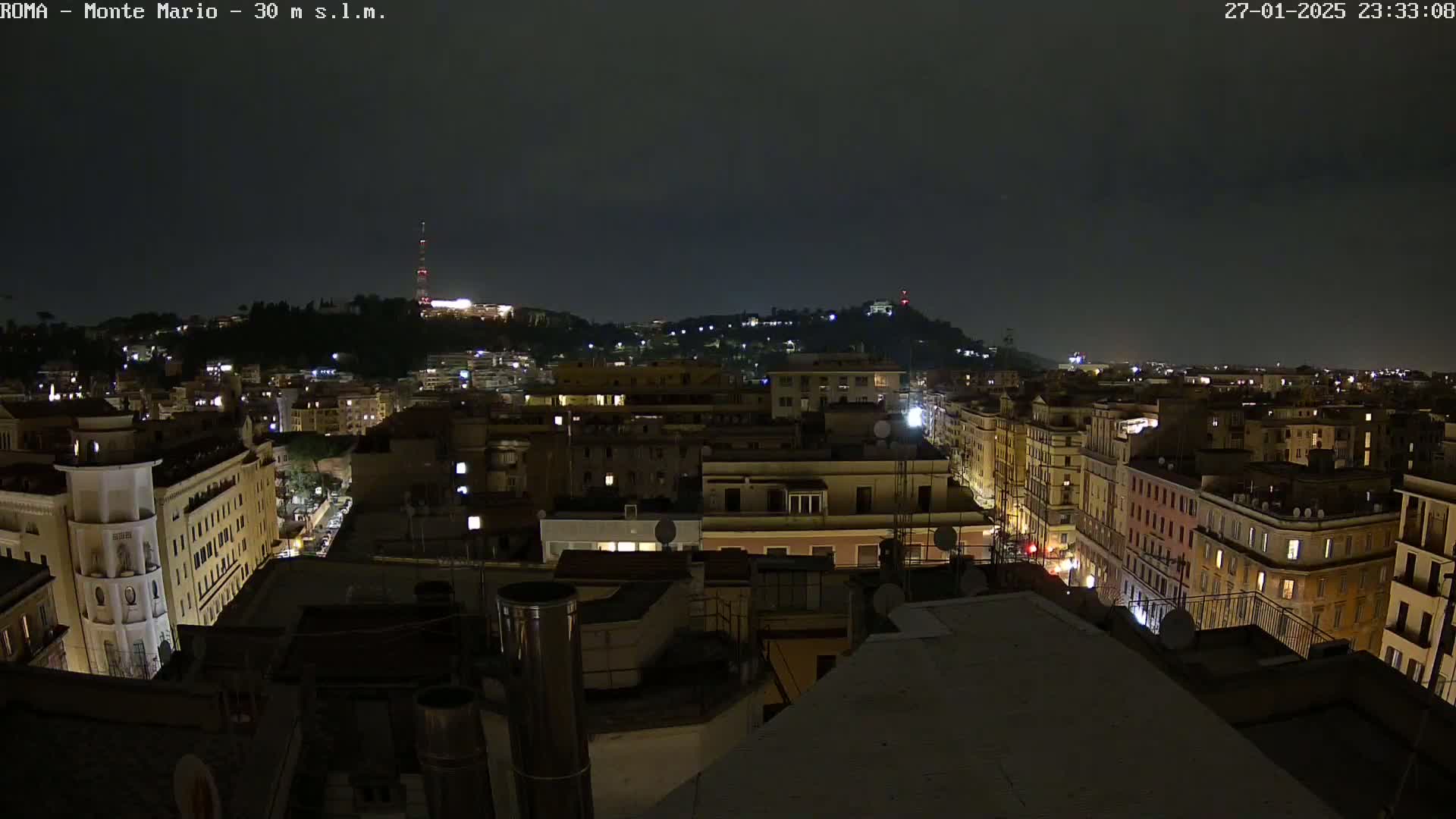 A nighttime view of a city with dimly lit buildings and streets under a dark, cloudy sky.