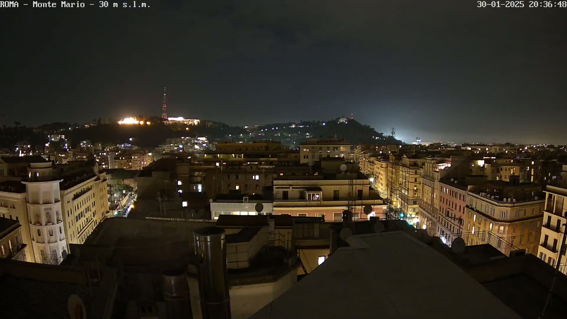 A nighttime view of a city with buildings lit up, under a dark sky.