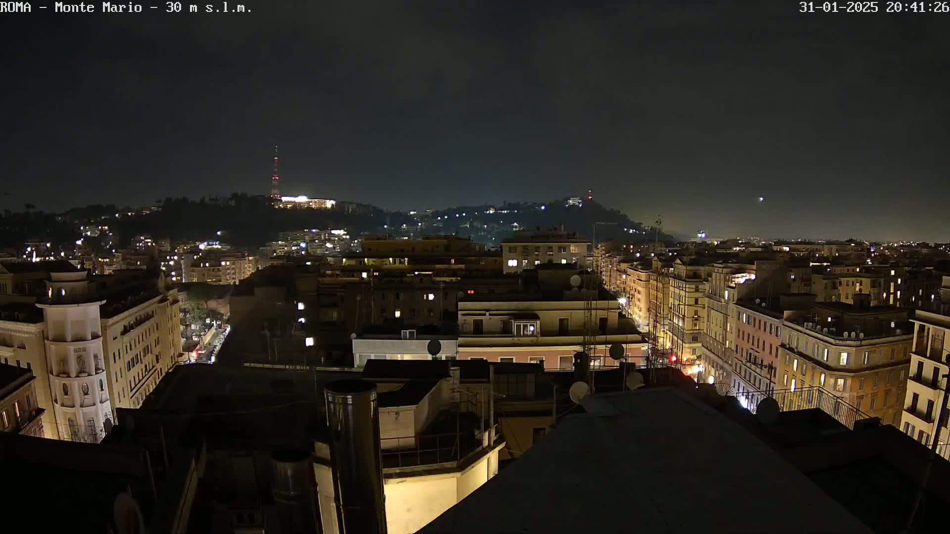 A nighttime view of a city with illuminated buildings and streets, under a dark sky.