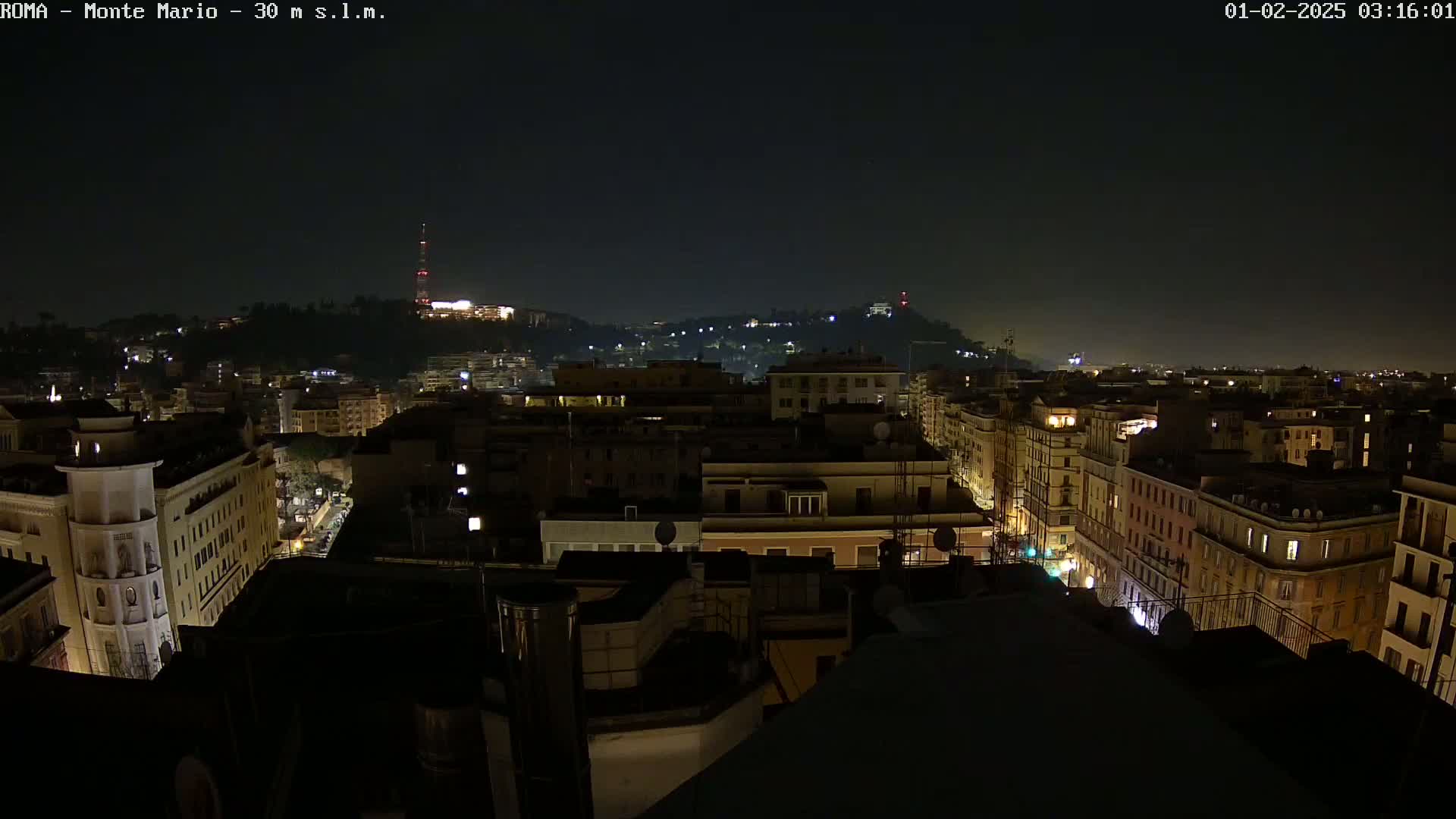 A nighttime, aerial view of a city with dimly lit buildings and streets, under a dark sky.