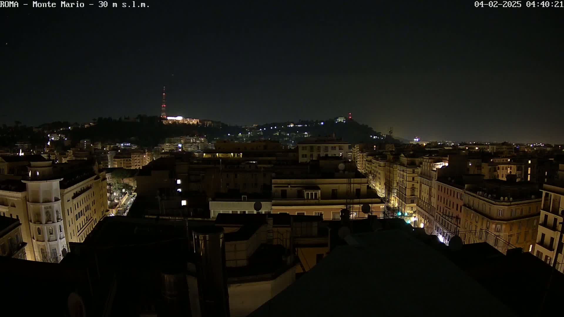 A nighttime cityscape with dimly lit buildings and streets, under a clear, dark sky.