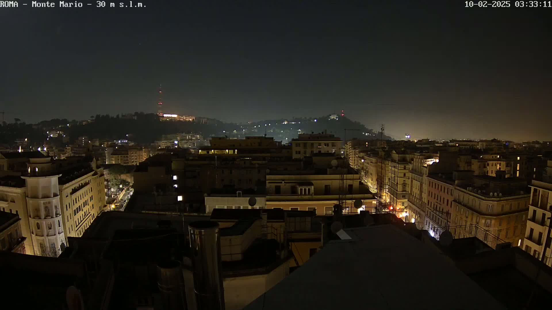 A nighttime view of a city, with dimly lit buildings extending into the distance under a dark sky.