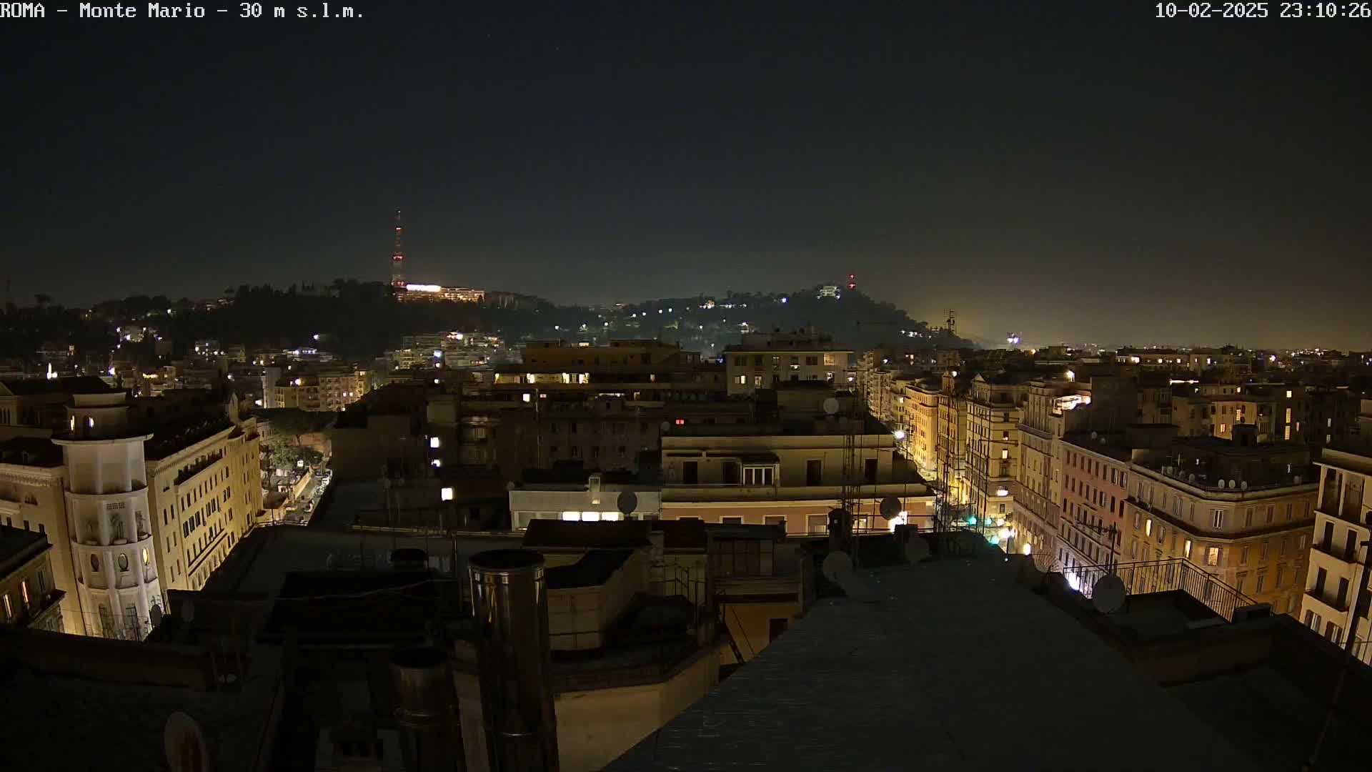 A nighttime view of a city, showing many buildings lit up against a dark sky.