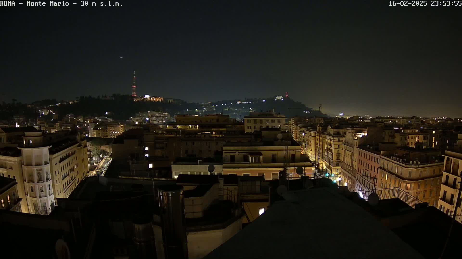 A nighttime view of a city with illuminated buildings and streets, under a dark, clear sky.