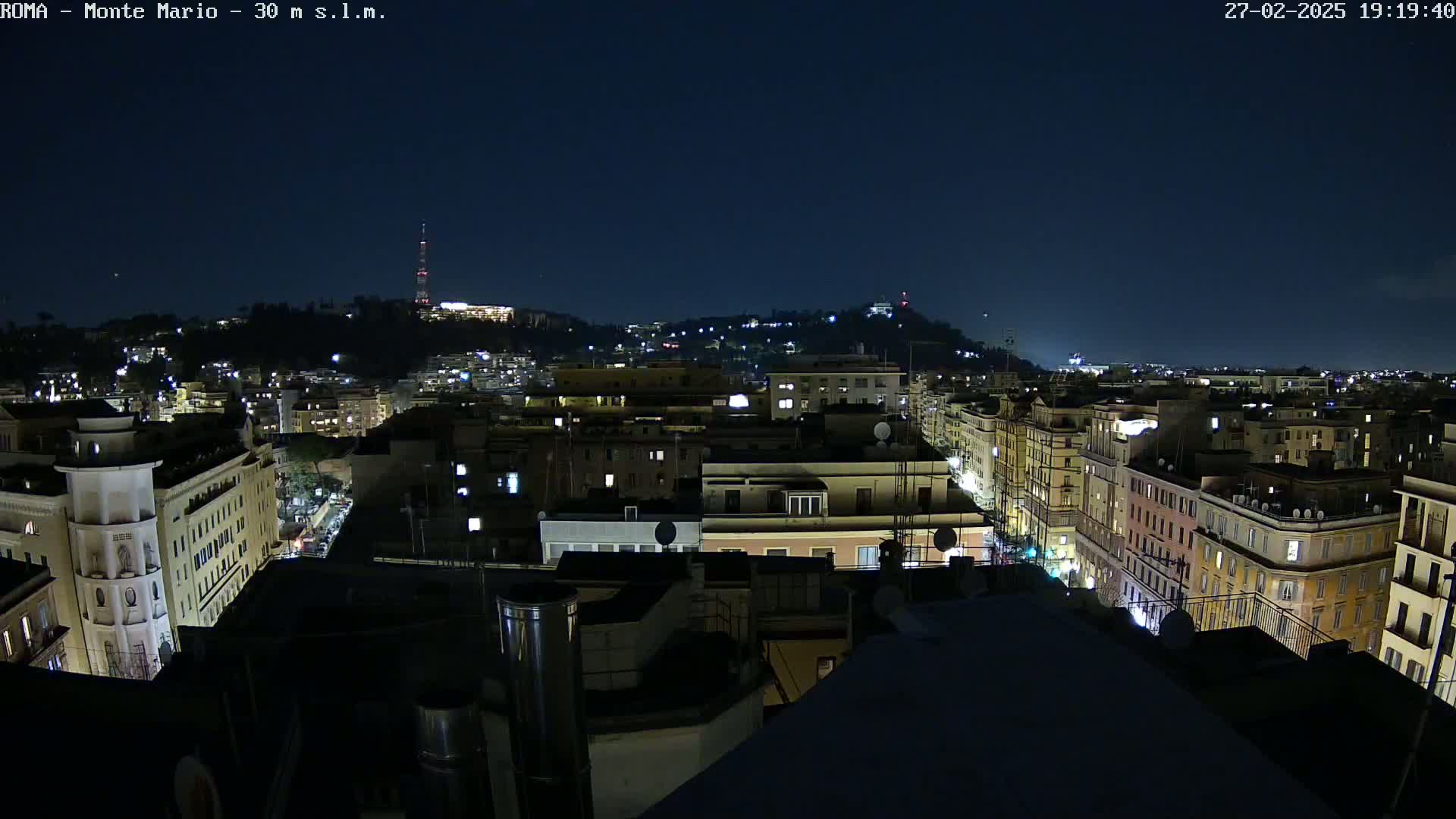 A nighttime view of a city illuminated with lights, under a clear, dark sky.