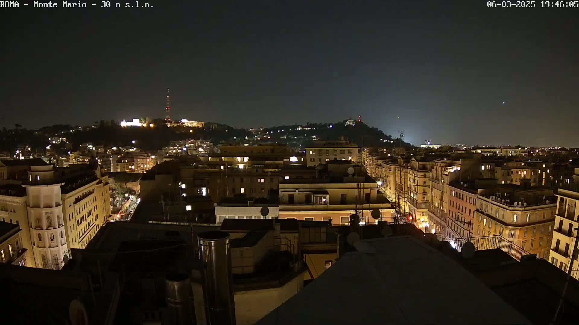 A nighttime view of a city, showing many buildings illuminated with streetlights under a clear, dark sky.
