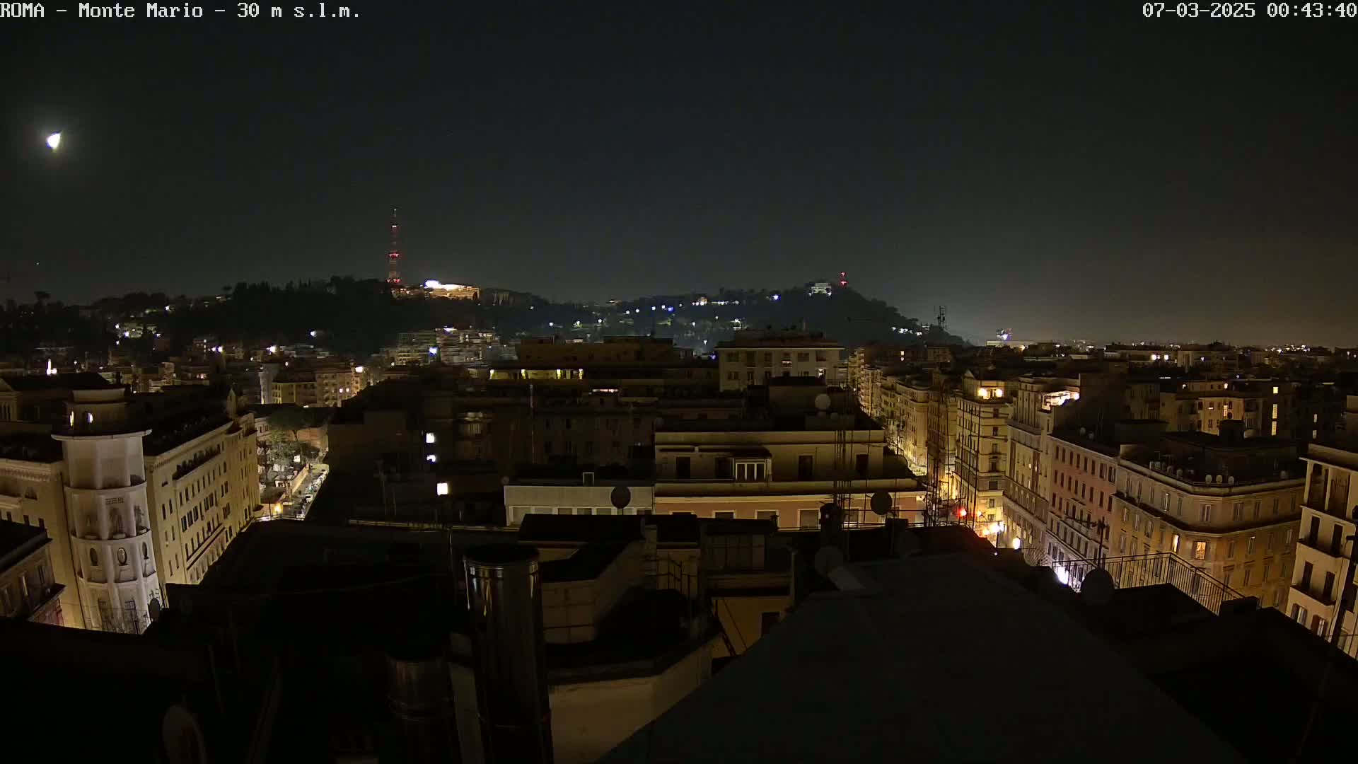 A nighttime view of a city with dimly lit buildings and streets, under a clear, dark sky.