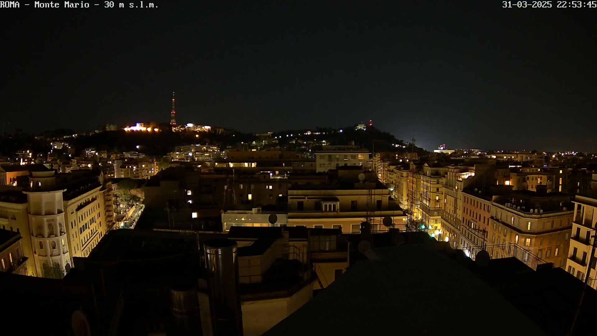 A nighttime cityscape of buildings with scattered interior lights, under a clear, dark sky.