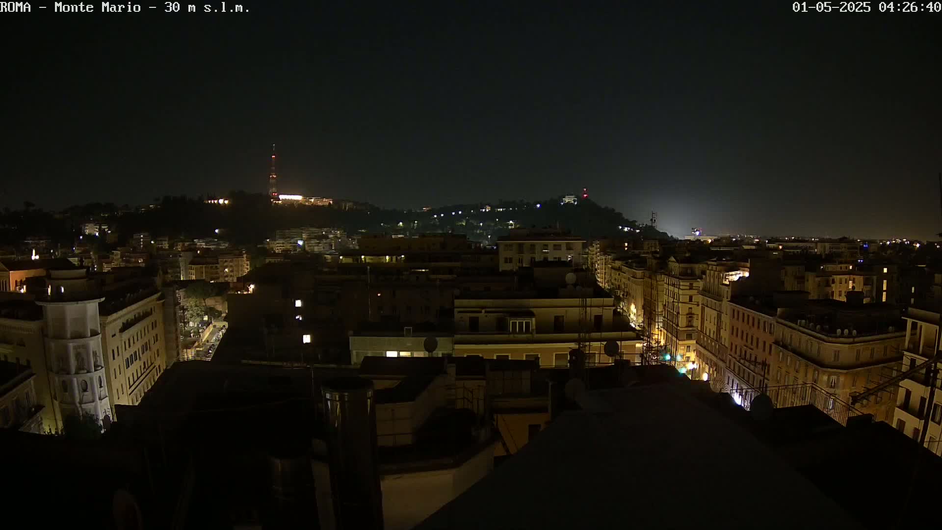 A nighttime view of a city, with dimly lit buildings stretching into the distance under a dark sky.