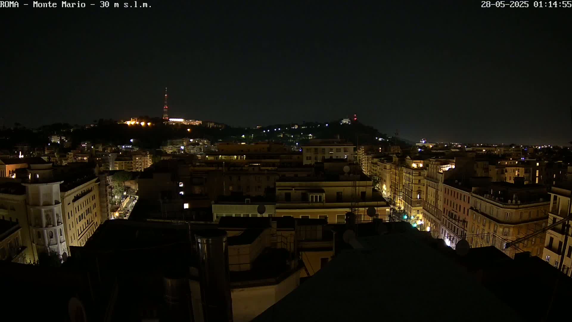 A nighttime, aerial view of a city, showing numerous buildings illuminated against a dark sky.