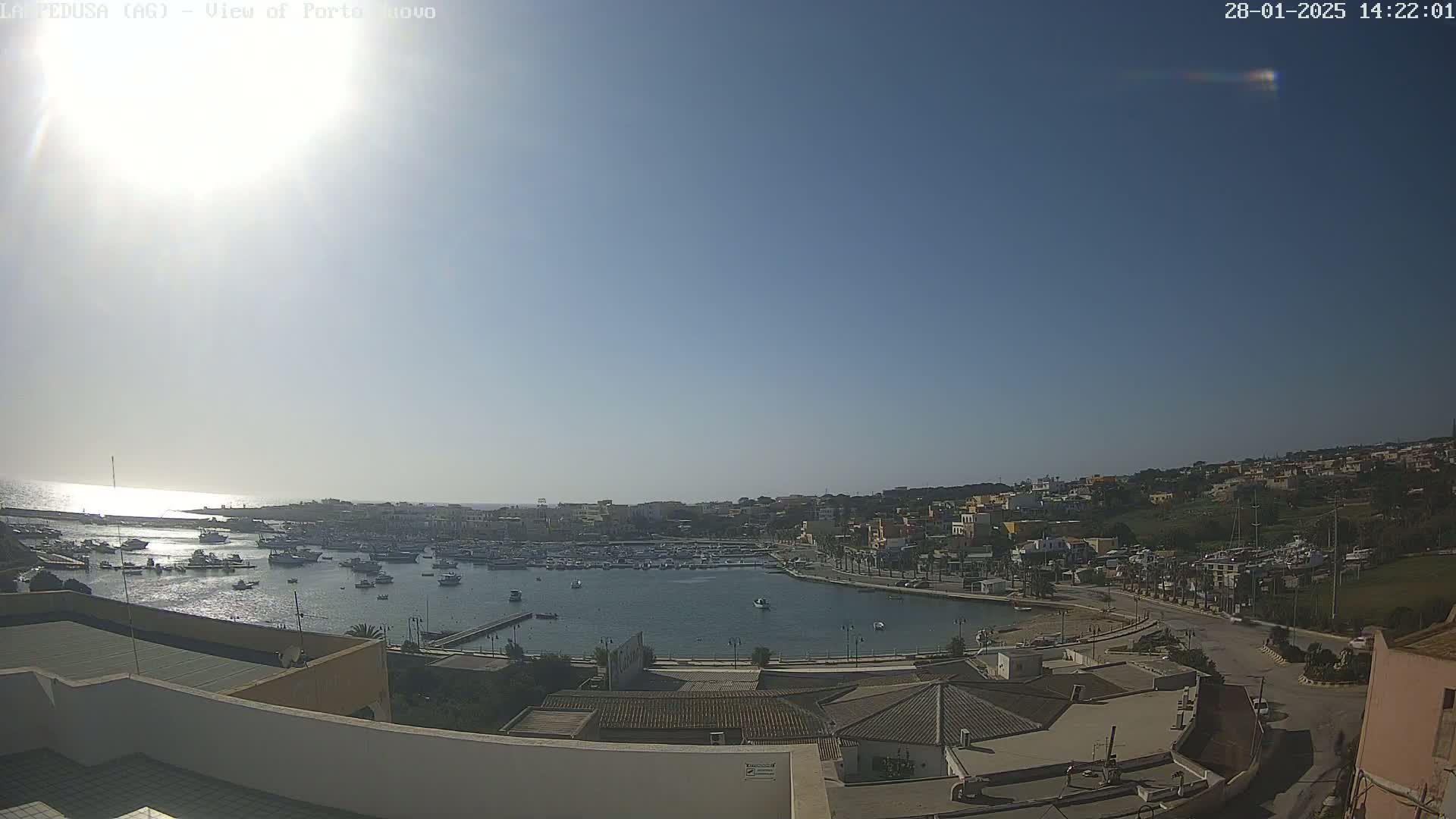 A sunny, clear day overlooks a harbor filled with boats and a town nestled on a hillside.