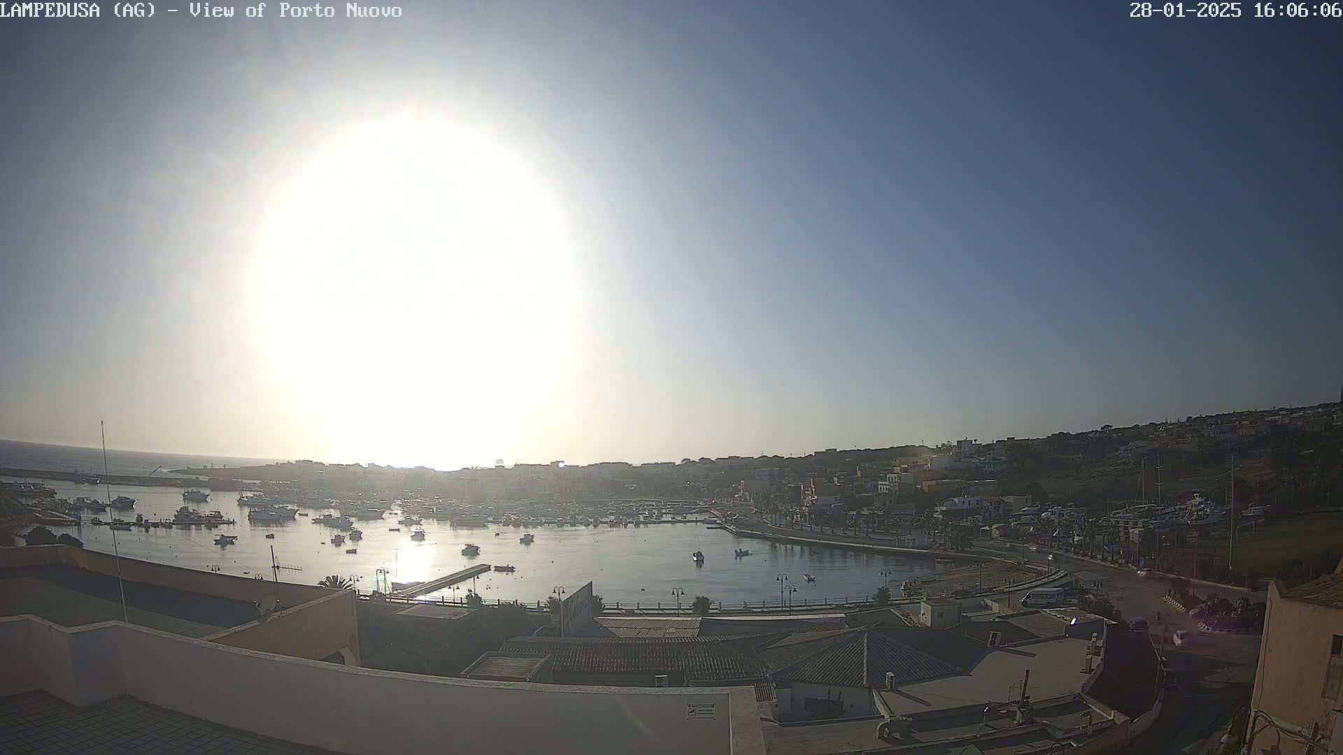 A sunny, clear day overlooking a harbor filled with boats and buildings along a coastline.