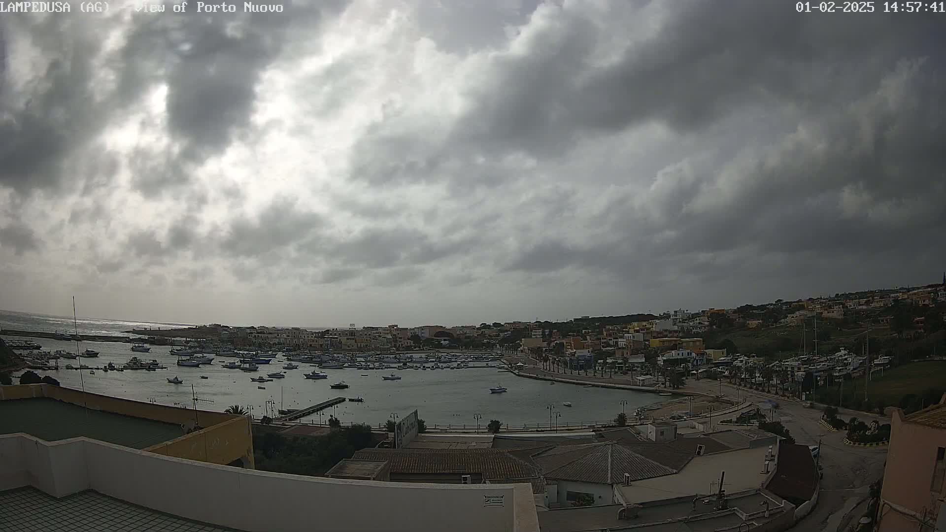 A harbor filled with numerous boats is situated beneath a cloudy sky.