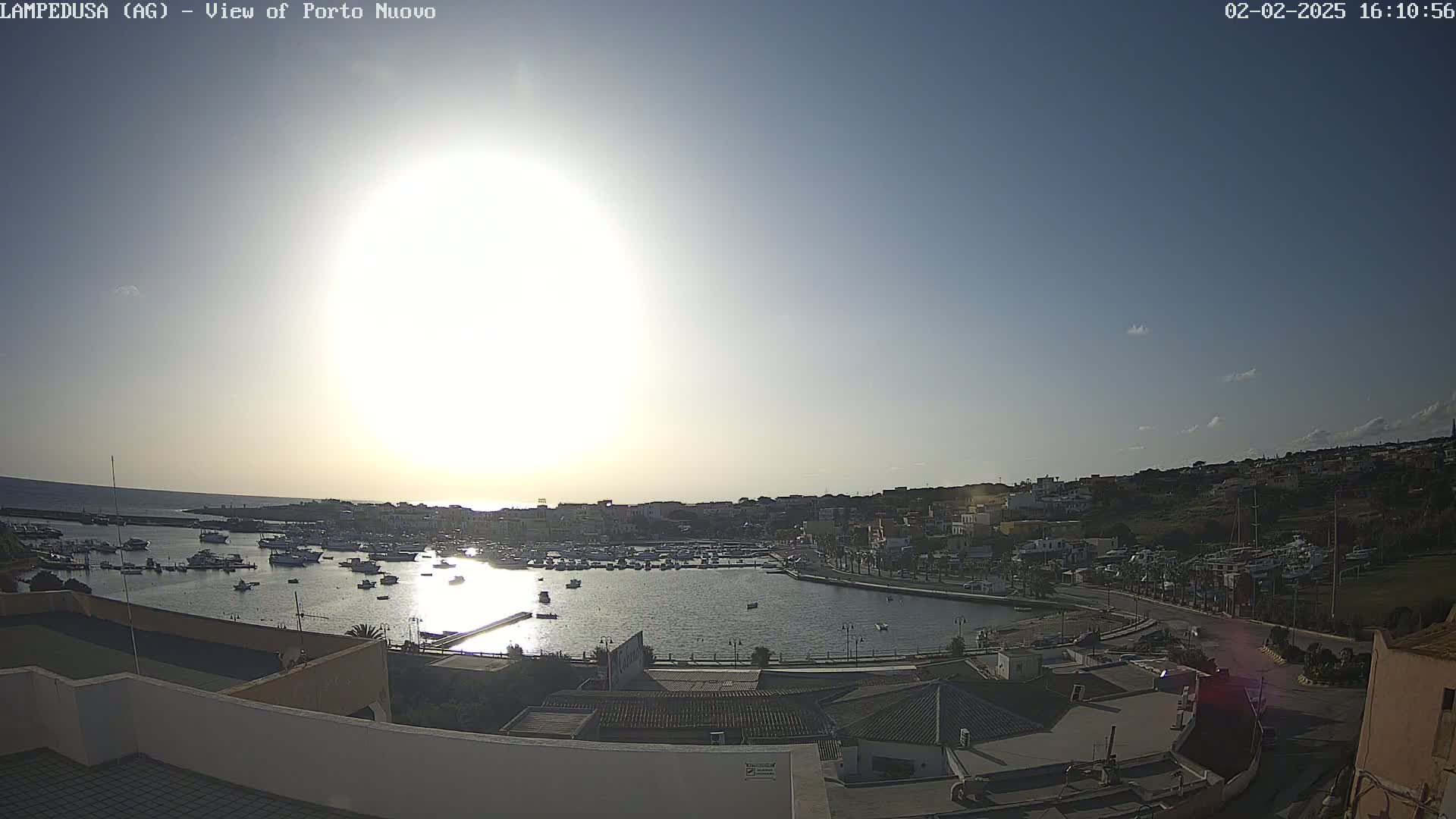 A sunny day overlooking a harbor filled with boats and a town nestled against a hillside.