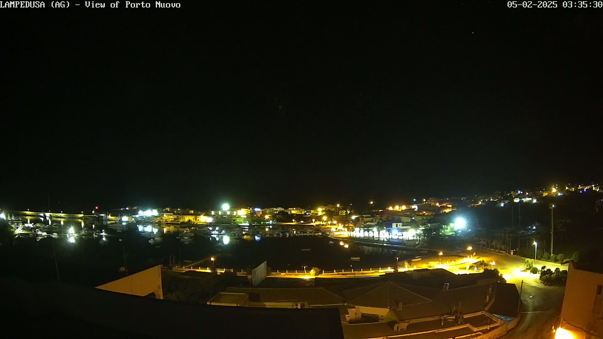 A nighttime view of a harbor town illuminated by lights, under a clear, dark sky.
