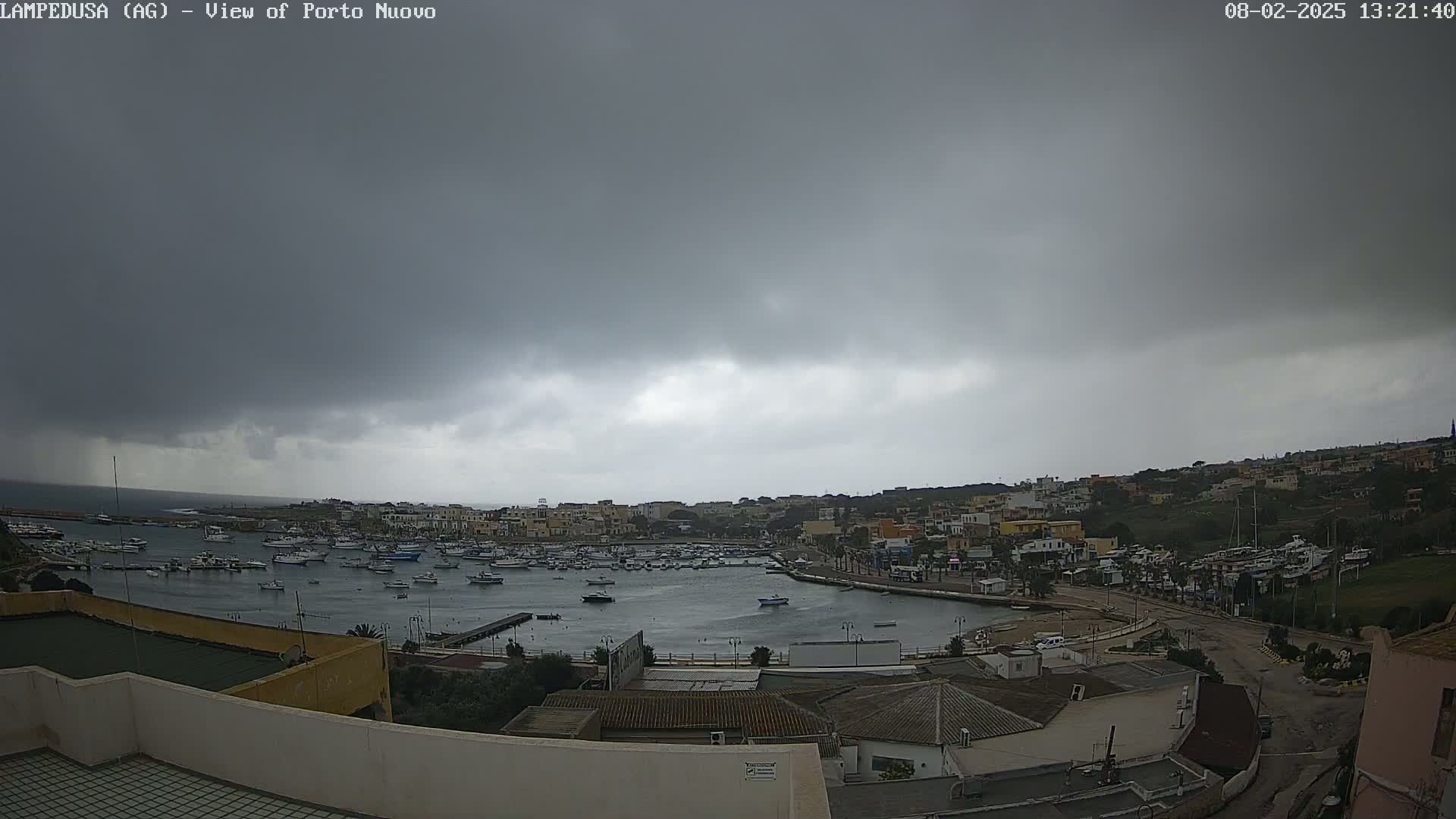 A harbor filled with boats is situated below a dark, overcast sky.