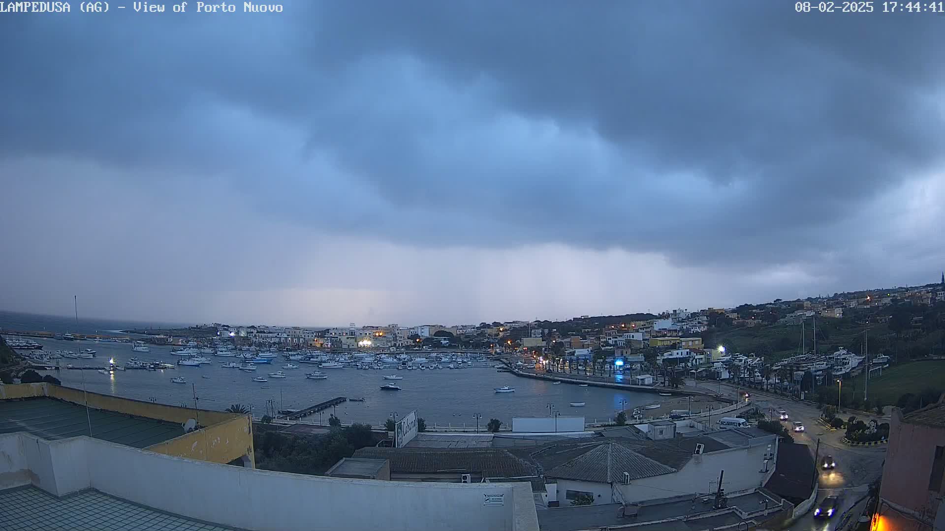 A harbor filled with boats is seen under a dark, stormy sky.