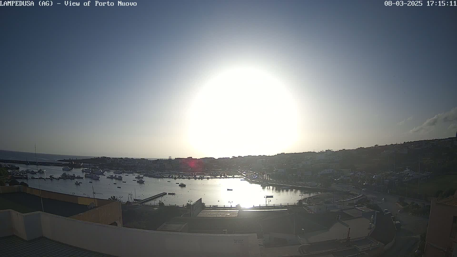 A bright, sunny day overlooks a harbor filled with boats and a town built along a hillside.
