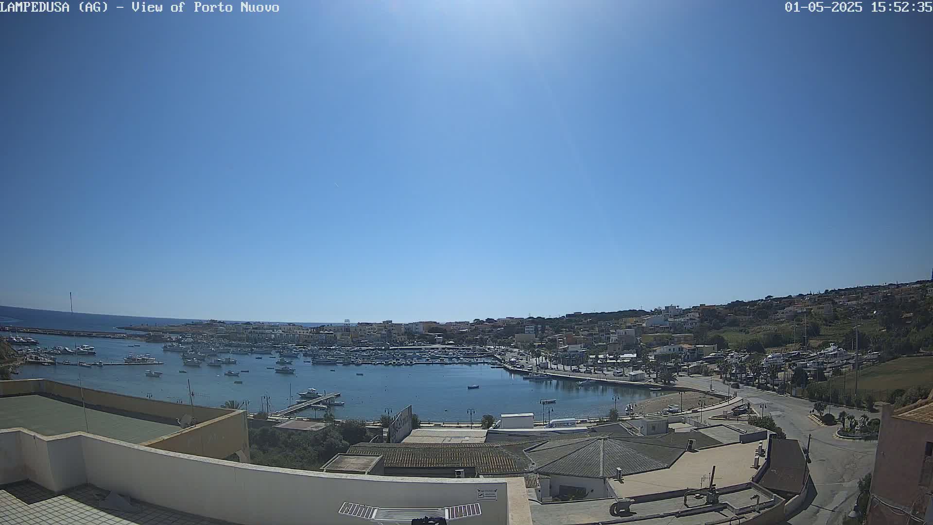 A harbor filled with boats is nestled in a town under a clear blue sky.