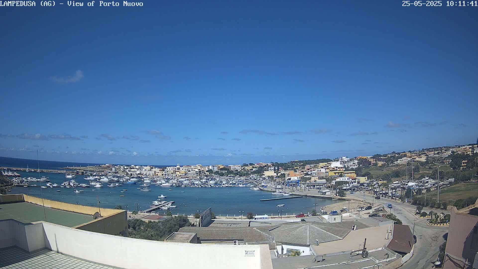 A harbor filled with boats is nestled within a town under a clear blue sky.