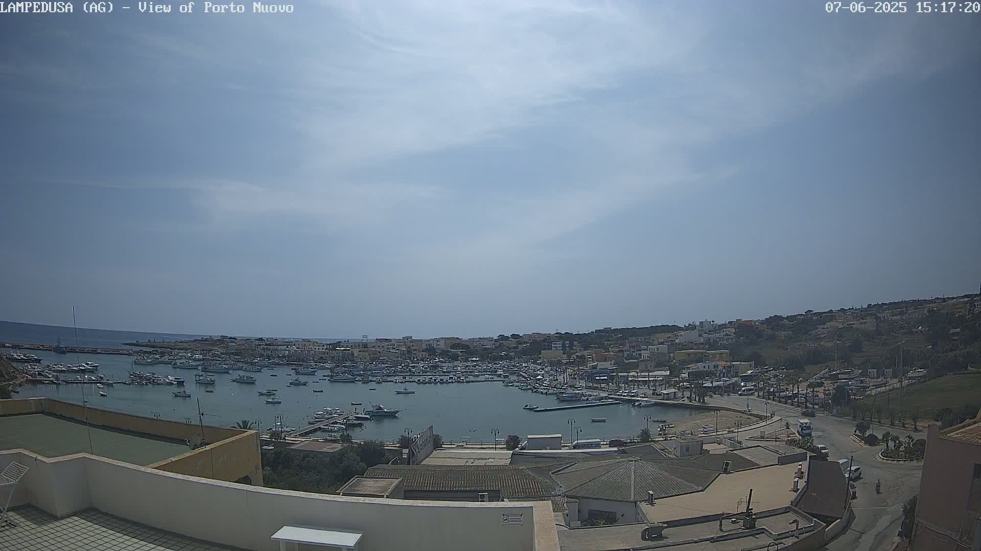 A harbor filled with boats is visible from an elevated vantage point on a partly sunny day.