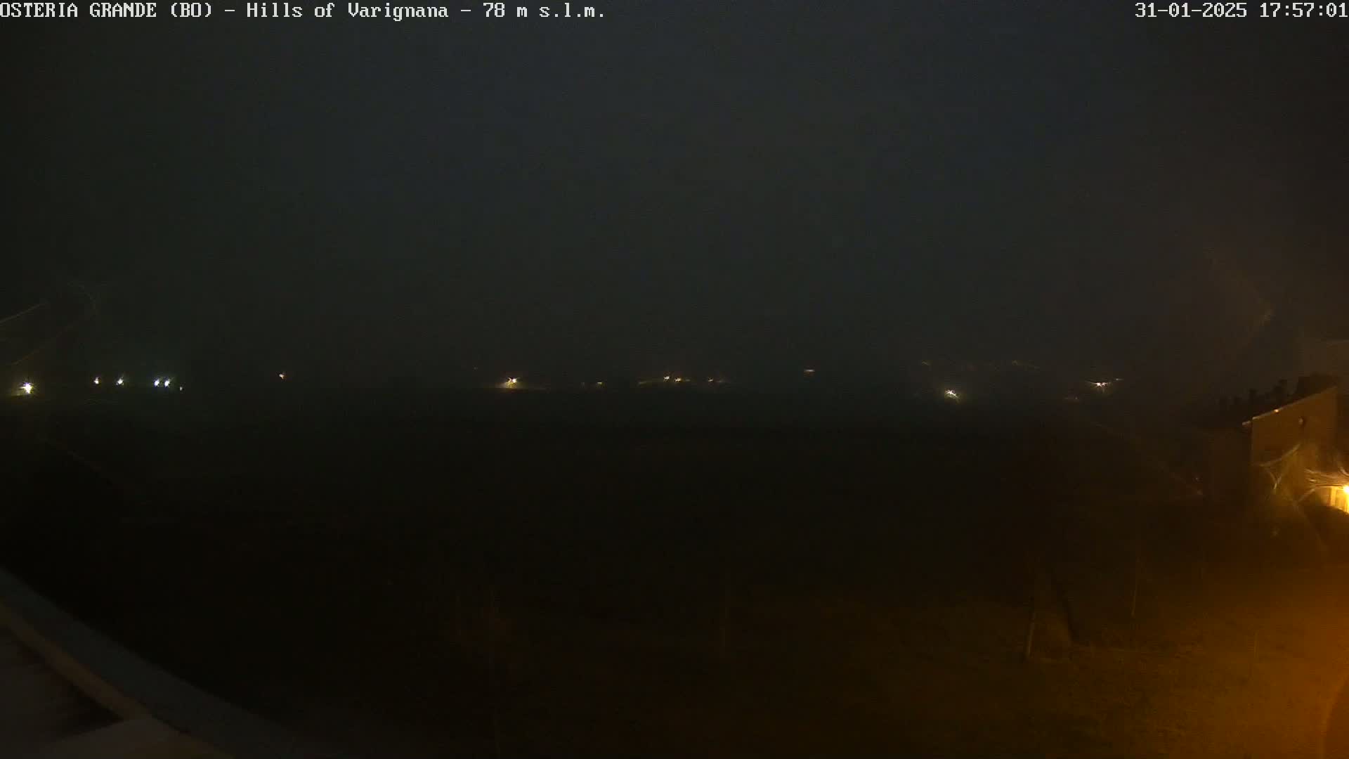 A nighttime view of a foggy landscape with faint lights visible in the distance.