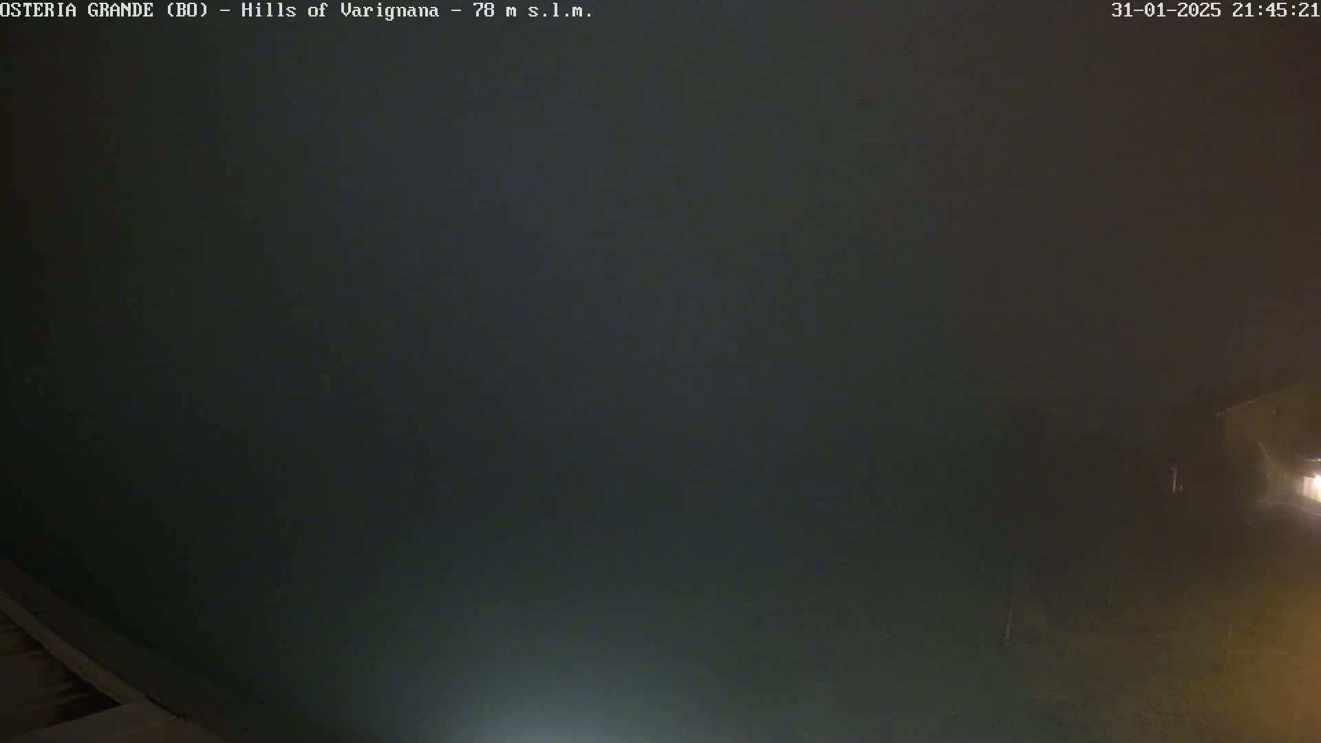 A dark, foggy night scene shows a portion of a building in the lower right corner.