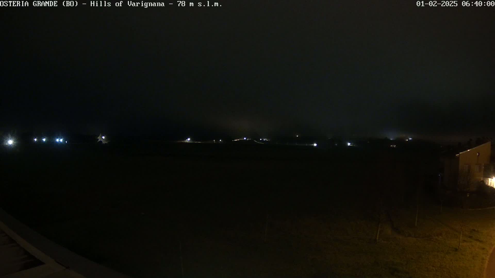 A dark, foggy nighttime scene shows dimly lit buildings and a road in the distance.