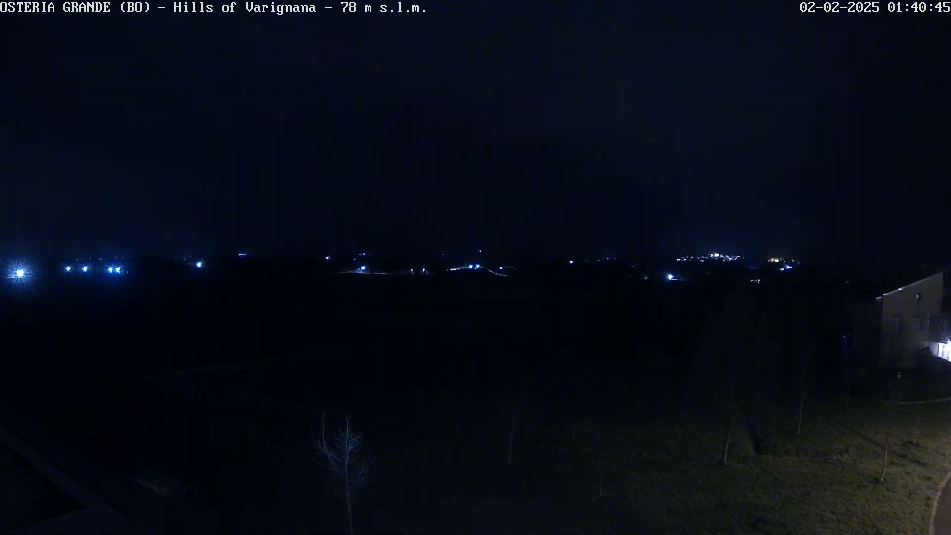 A nighttime view of a dark landscape with sparsely scattered lights in the distance under a clear, dark sky.