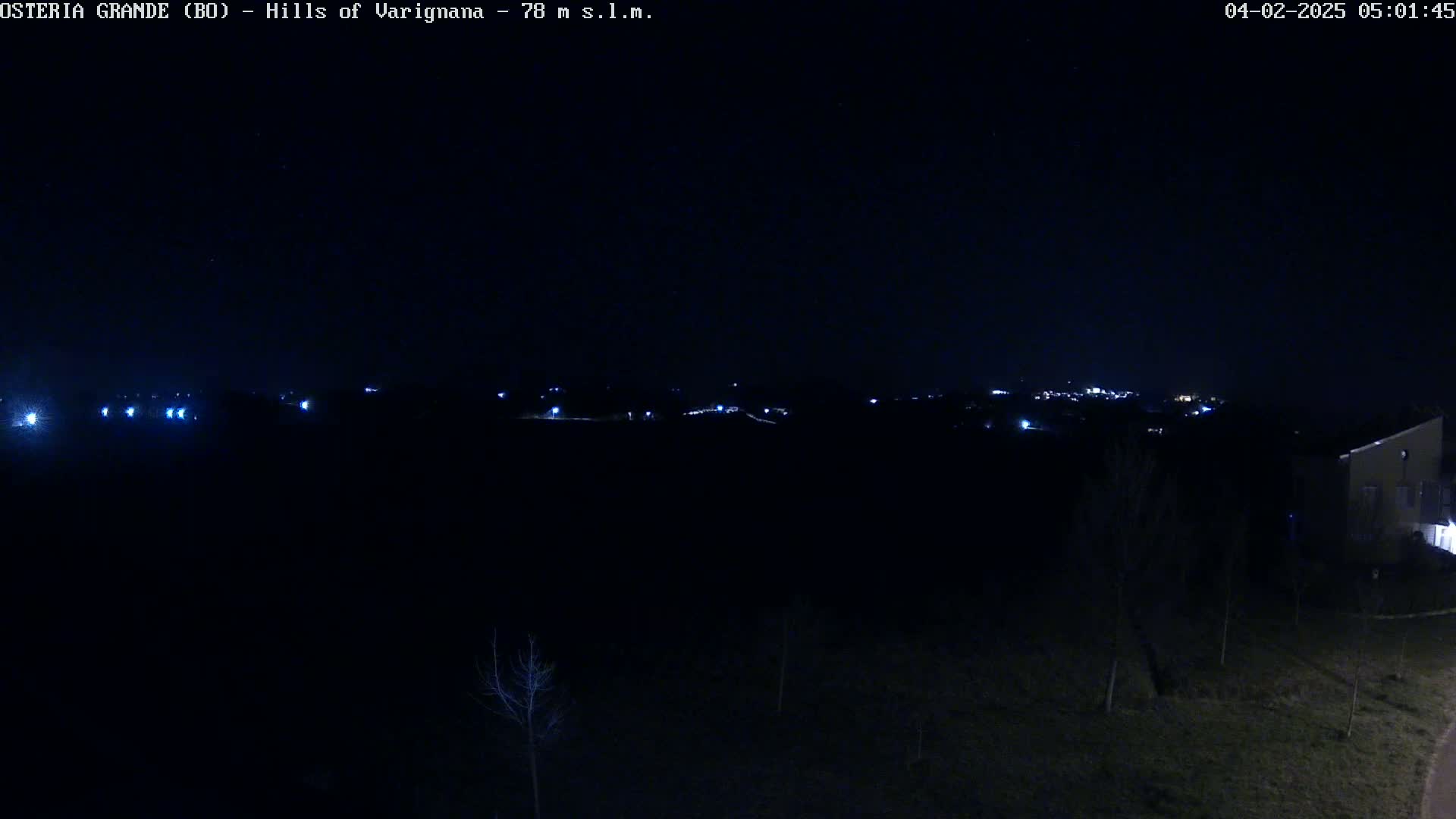 A nighttime, dark view of a sparsely lit landscape with a distant town visible on the horizon.